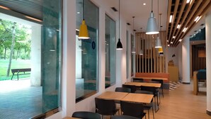 A modern indoor space with large windows, wooden tables, and black chairs. - Holiday Inn Express Logrono Rioja by IHG (Logroño)