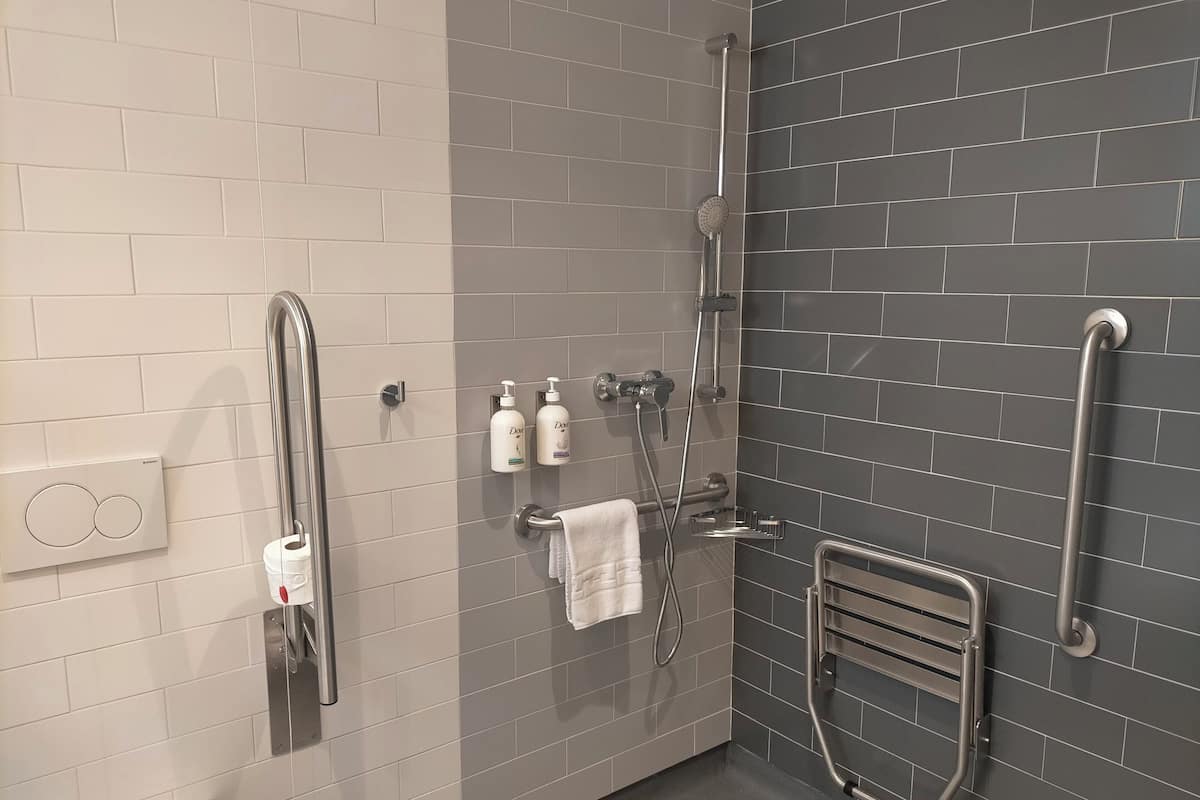 Un baño moderno con ducha, inodoro y secamanos.