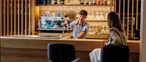 A bar area with a counter, bar stools, and a variety of bottles and glasses on shelves.