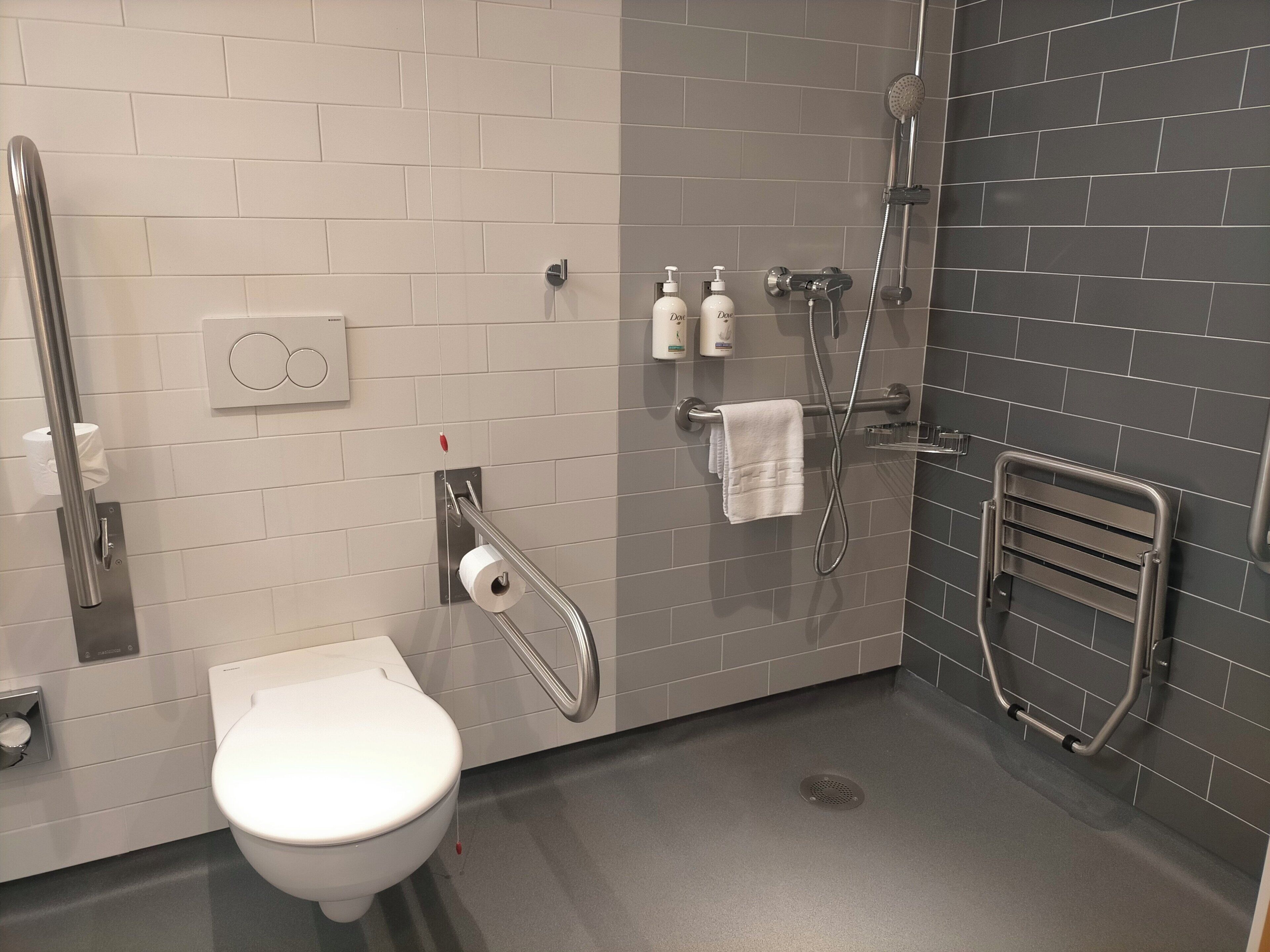 Un baño moderno con inodoro, ducha y secador de manos.