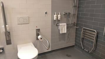 Un baño moderno con inodoro, ducha y secador de manos.
