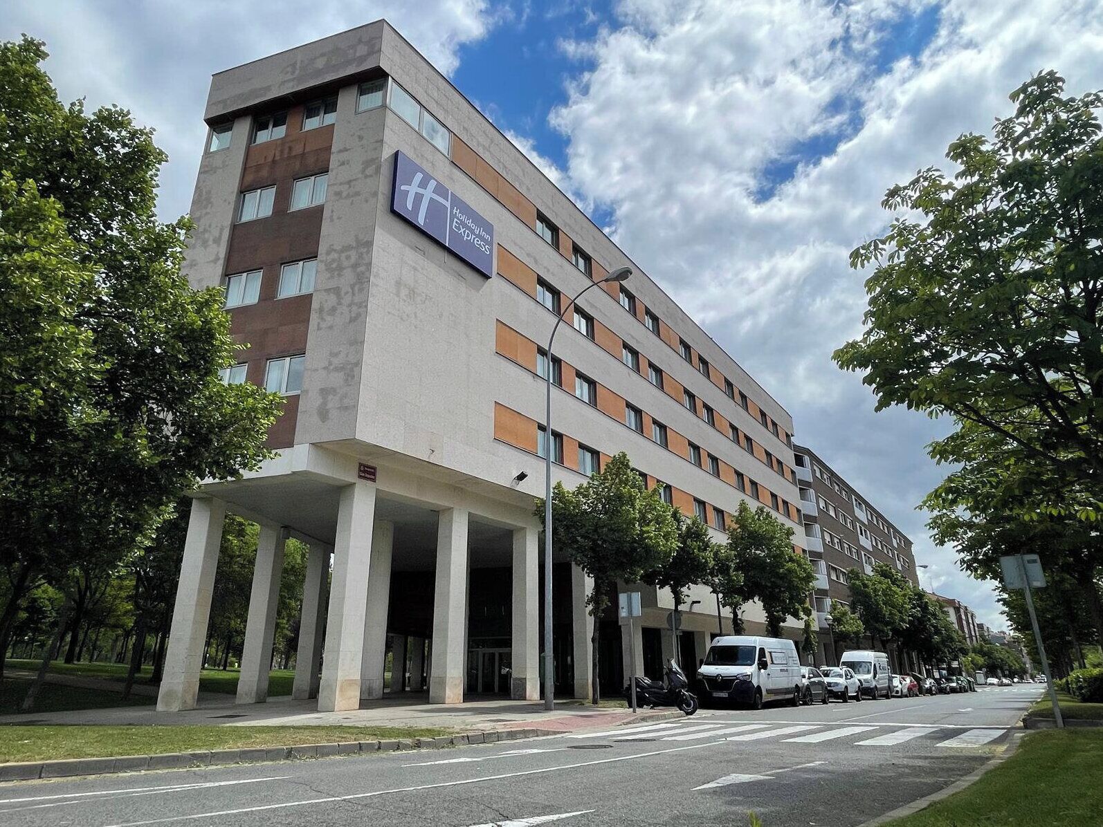 A modern hotel with a flat roof, multiple floors, and a prominent sign.