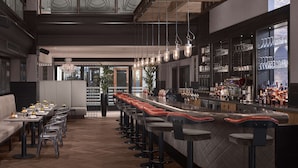 A modern bar area with a long counter, multiple stools, and a variety of bottles and glasses. - Radisson Blu Hotel, Leeds City Centre (Leeds)