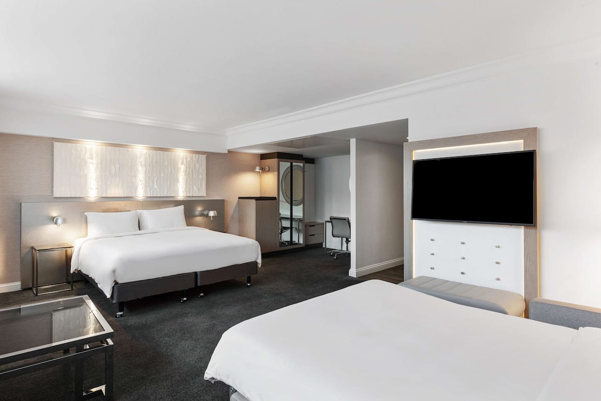 A hotel room with a large bed, a desk, a TV mounted on the wall, and a mirror.