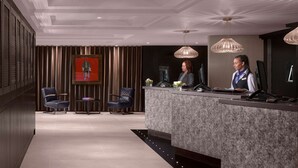 A modern hotel reception area with a marble counter, two receptionists, and a large painting on the wall. - Radisson Blu Hotel, Leeds City Centre (Leeds)