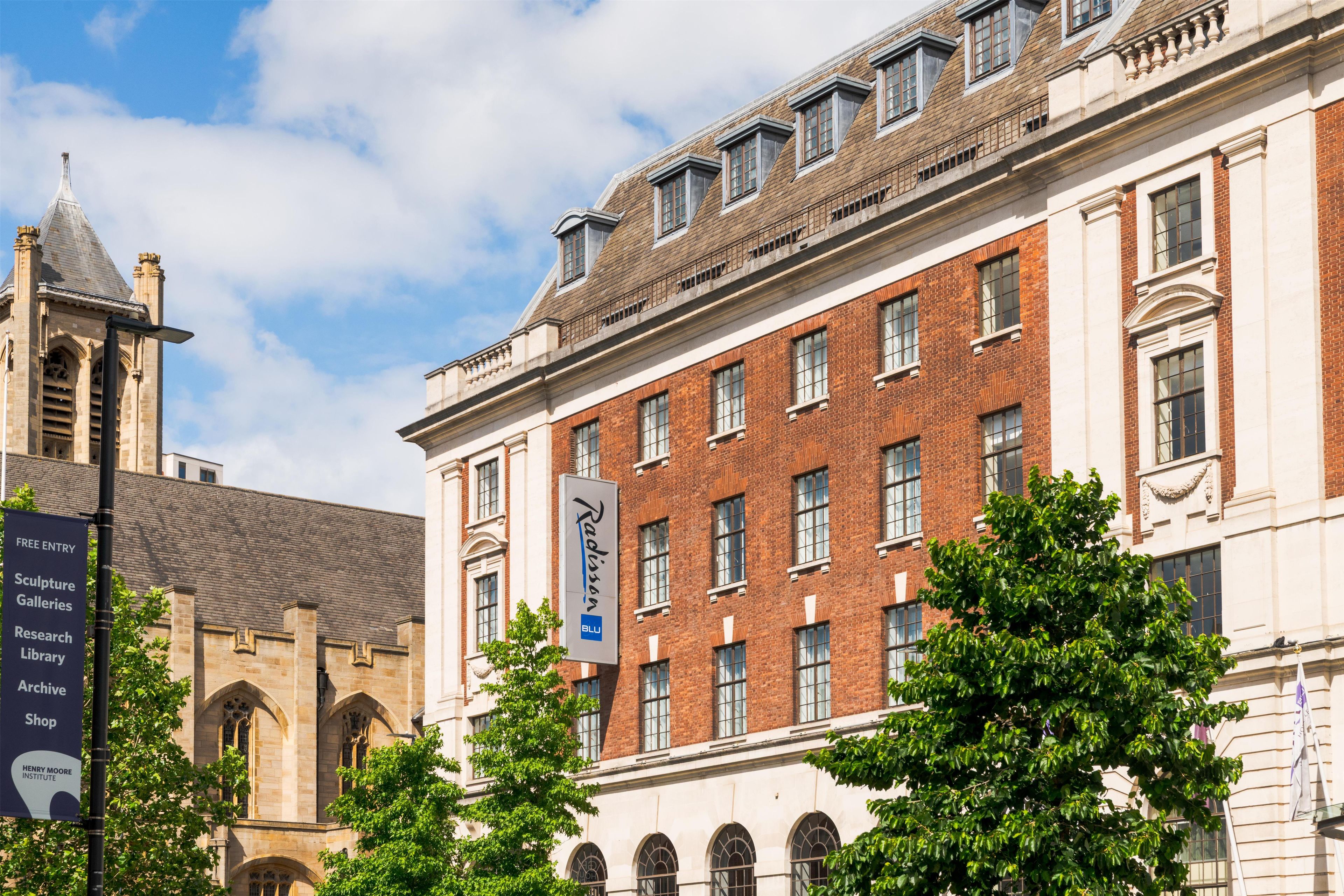 A historic building with a prominent clock tower and a modern extension with large windows.