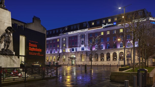 A historic building with a Radisson BLU hotel sign, a statue, and a well-lit plaza. - Radisson Blu Hotel, Leeds City Centre (Leeds)