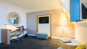 A modern hotel room with a desk, chair, sofa, and a TV mounted on the wall. - Radisson Blu Hotel, Leeds City Centre (Leeds)