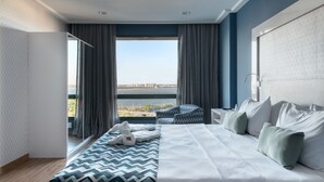 A modern hotel room with a large bed, a view of a bridge, and a balcony with a view of the water. - Comfort Suites Vitoria (Vitoria)