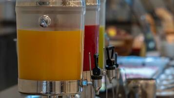 A beverage dispenser with multiple options, including orange juice, and a selection of yogurt cups and bowls.