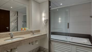 Un baño moderno con dos lavamanos, un espejo grande, cabina de ducha de vidrio y tocador con armarios.
