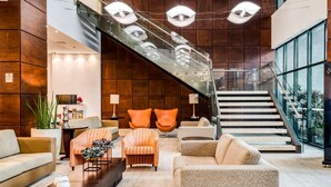A modern lobby with a staircase, seating area, and potted plants. - Comfort Suites Vitoria (Vitoria)
