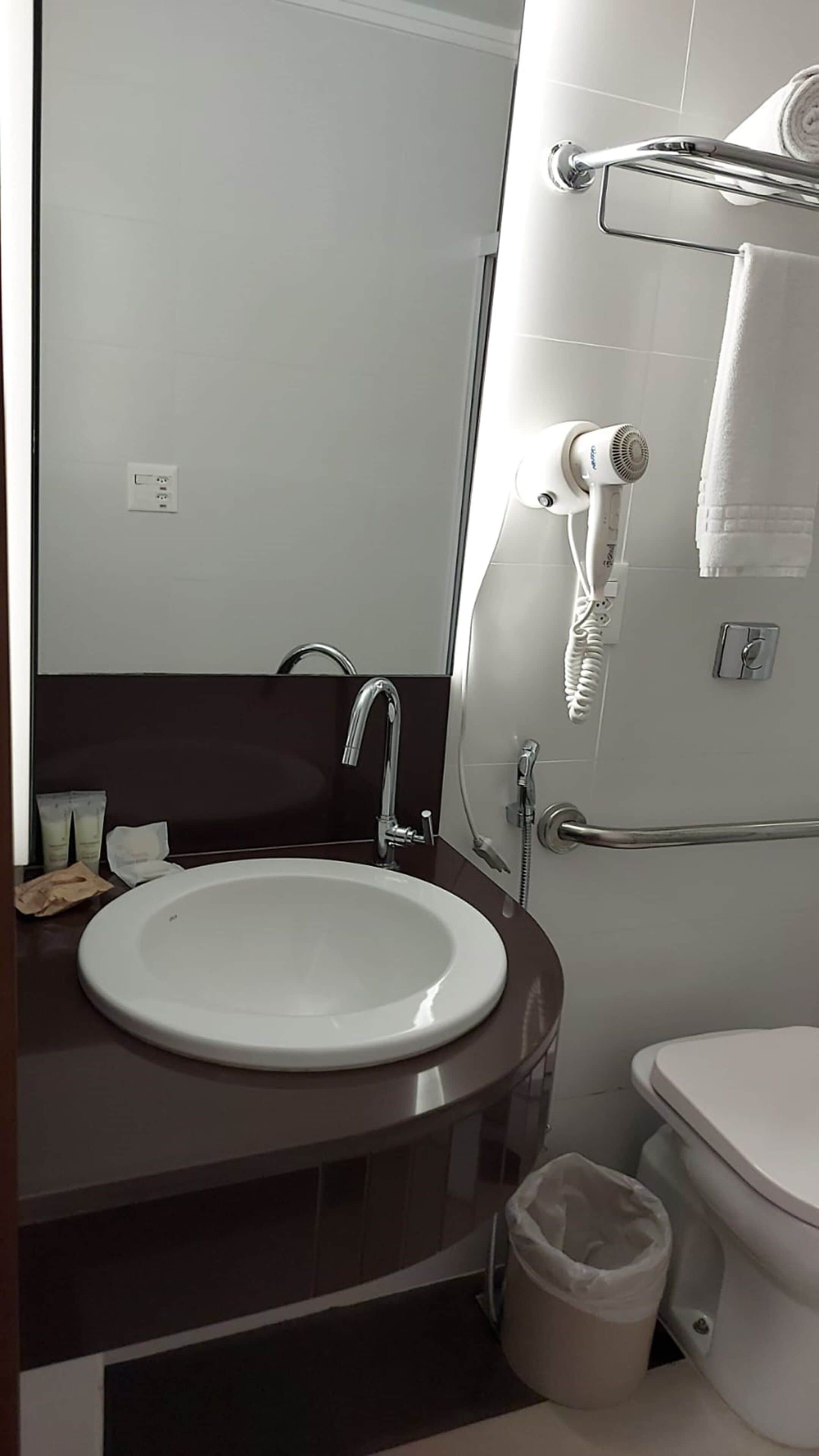A bathroom with a white sink, a mirror, a towel rack, and a toilet.