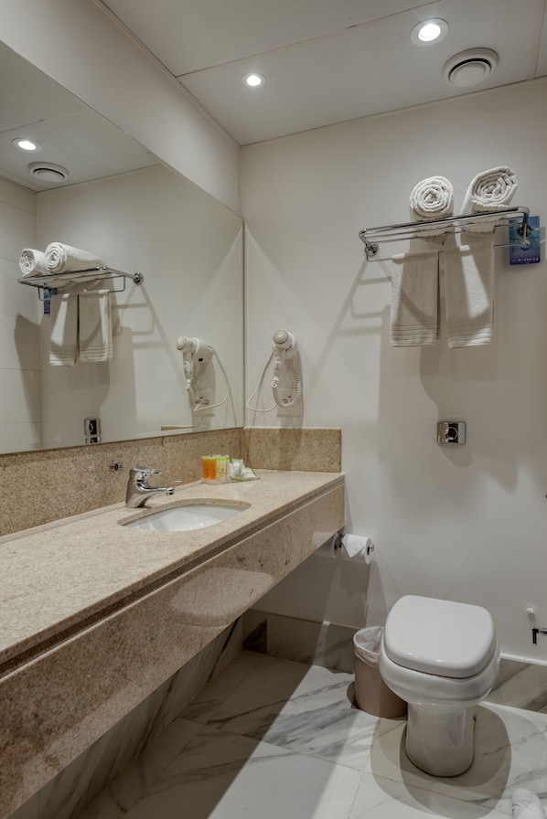 A modern bathroom with a marble sink, a toilet, and a towel rack with neatly rolled towels. - Comfort Suites Vitoria (Vitoria)