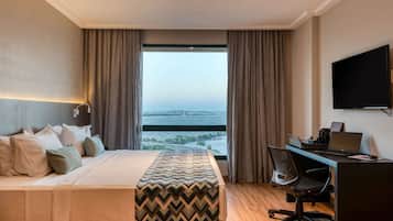 Una habitación de hotel con una cama, un escritorio con una computadora portátil, una silla y un televisor.