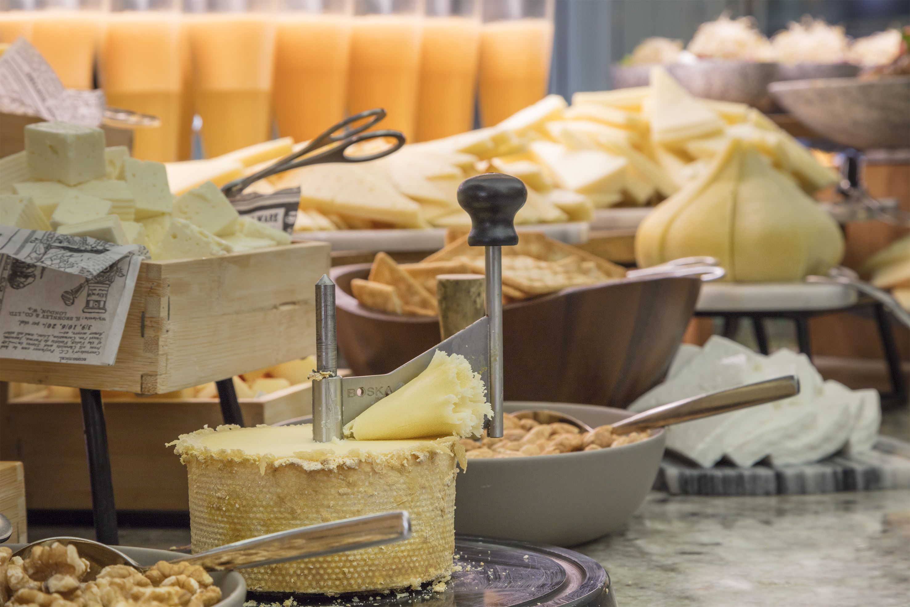 Une présentation de fromages et de fruits secs, comprenant différents types de fromages, des fruits secs et un trancheur à fromage.