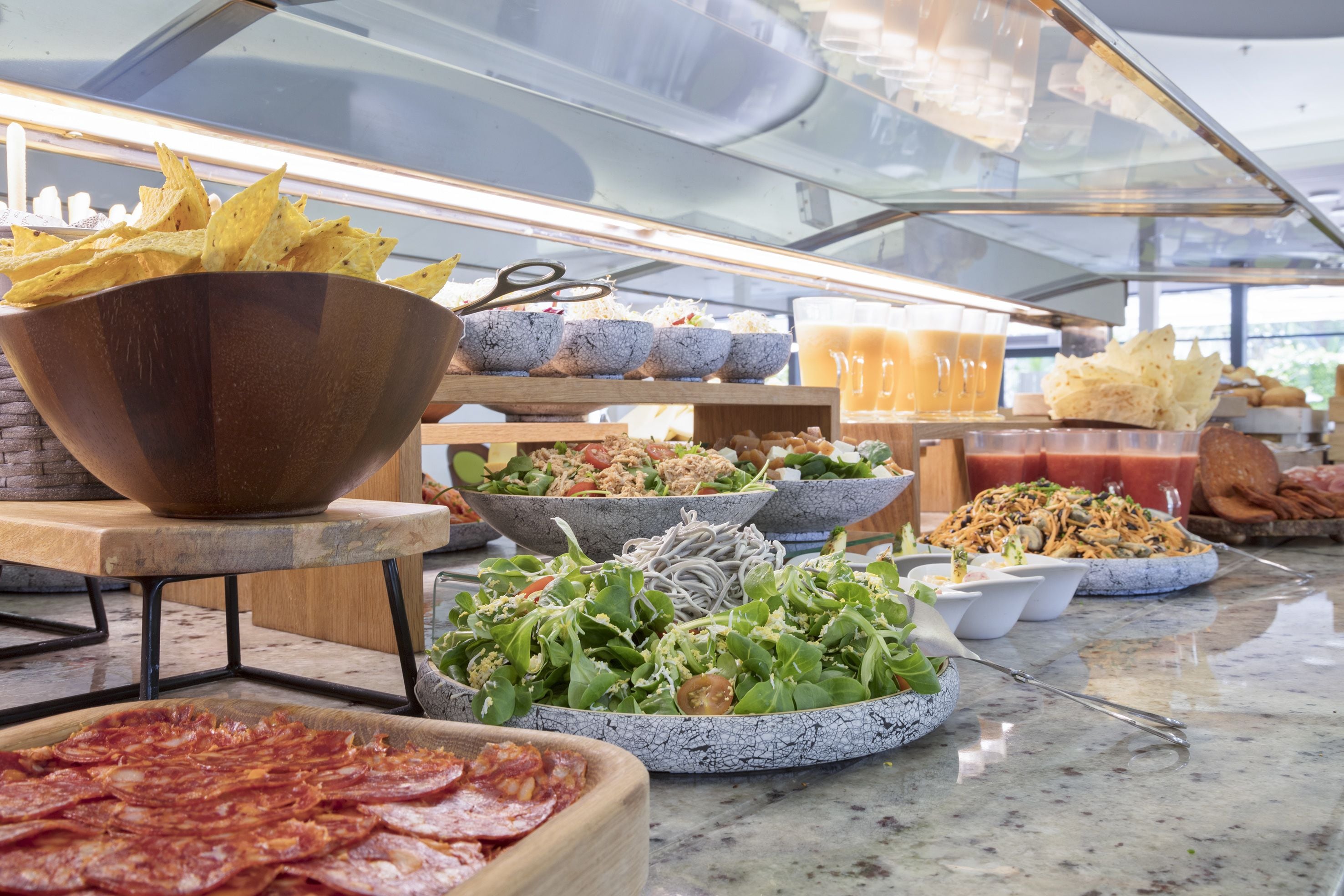A buffet with various food items including chips, salads, and meats.
