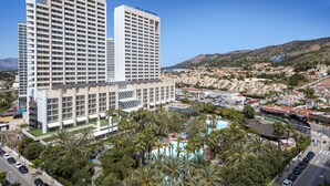 A hotel with multiple floors, a swimming pool, and a view of the surrounding town. - Melia Benidorm (Benidorm)