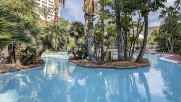 A pool area with palm trees and a clear blue sky.