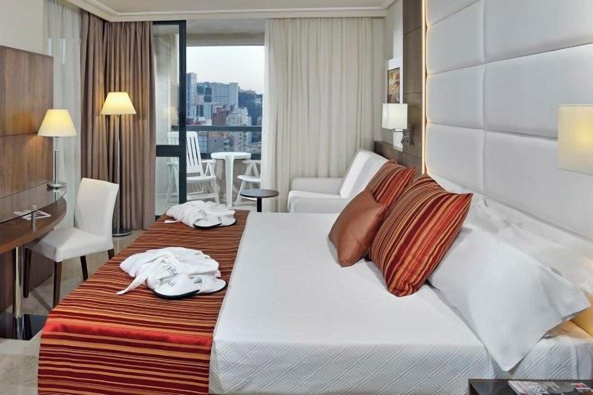 Una habitación de hotel con una cama, un escritorio, una silla y vistas a la ciudad.