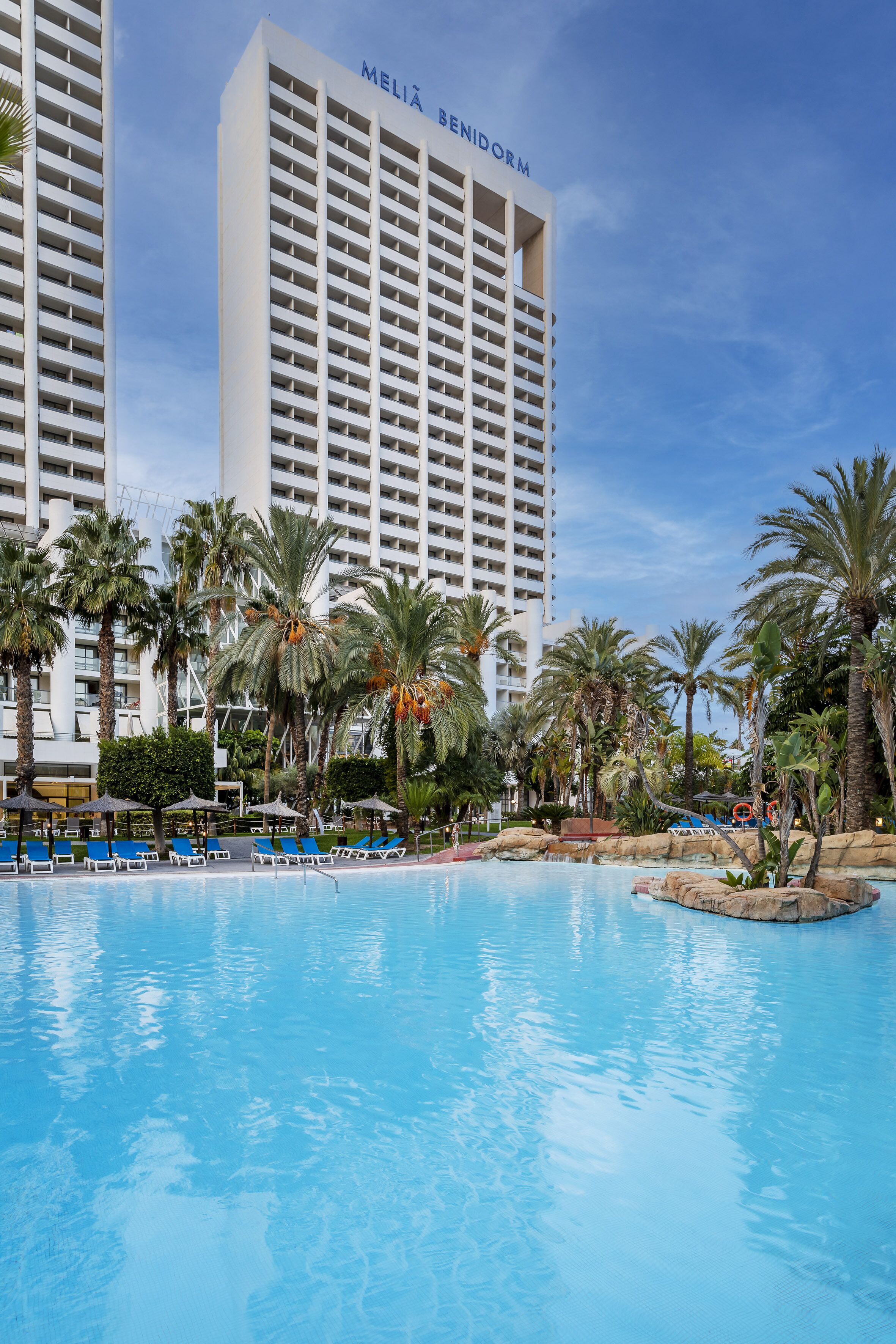 A hotel pool area with palm trees and a large building labeled "MELIA BENIDORM" in the background.