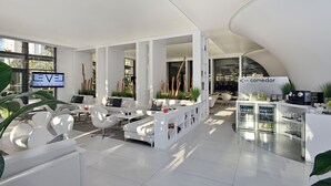 A modern, well-lit lobby with white furniture, a reception desk, and a sign indicating a dining area. - Melia Benidorm (Benidorm)