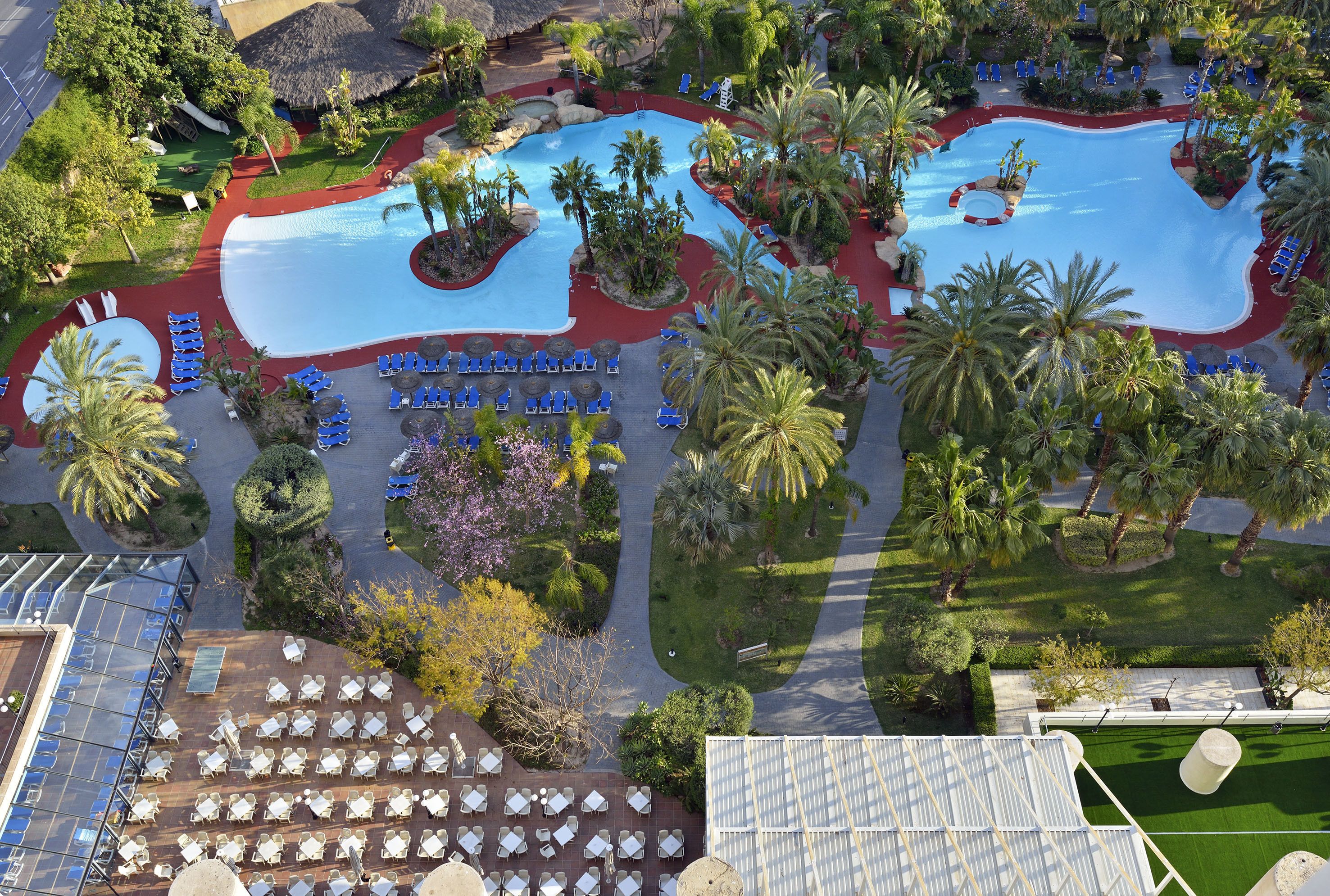 Ein Resort mit großem Pool, Palmen und Außenbereichen zum Sitzen.