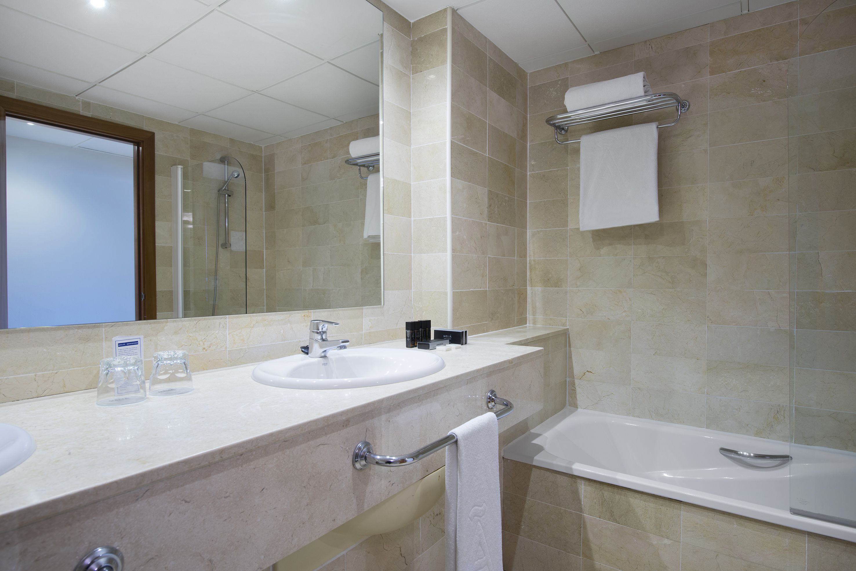 Een moderne badkamer met twee wasbakken, een grote spiegel, een douche en een bad.