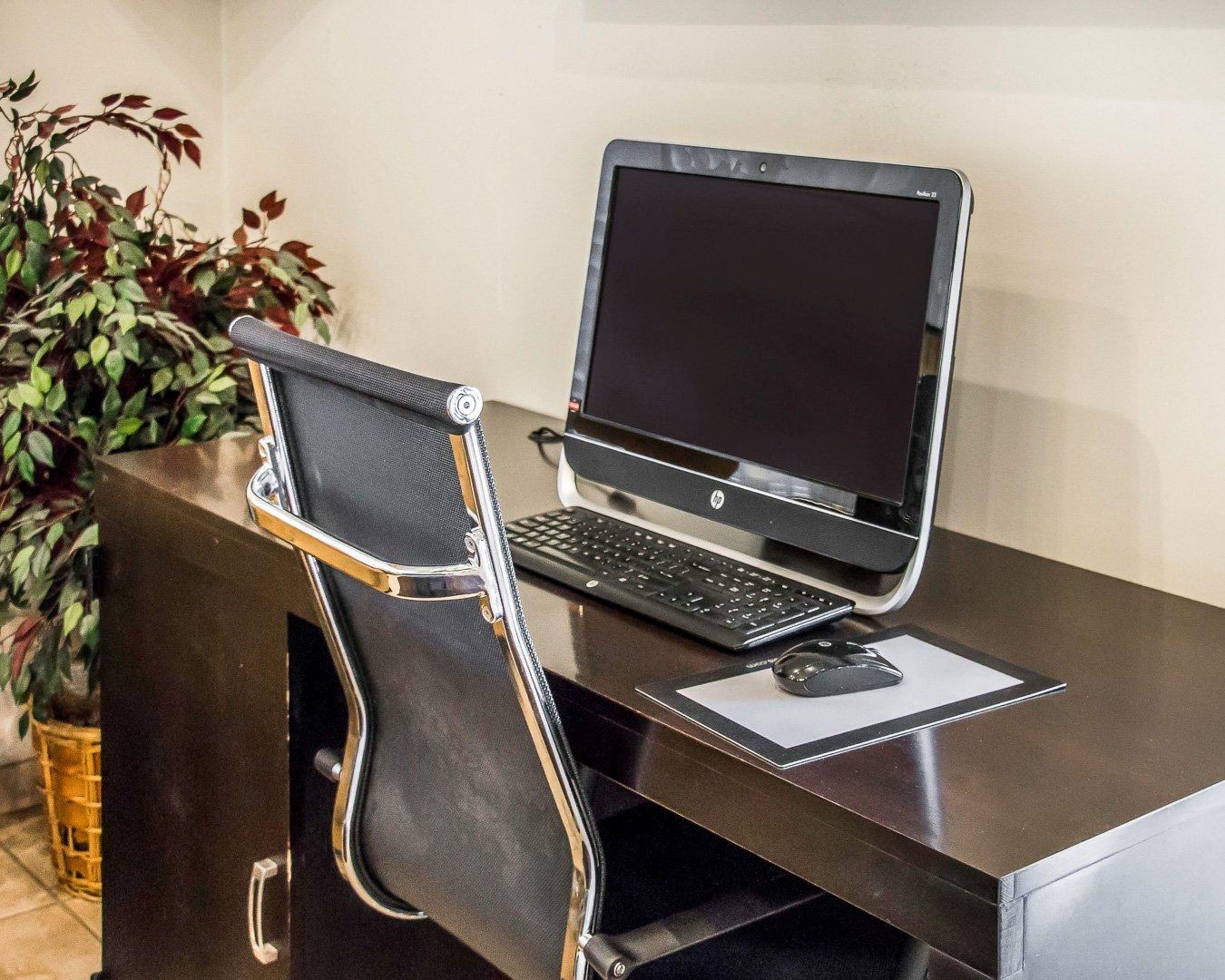 A laptop on a desk with a chair, a mouse, and a keyboard.