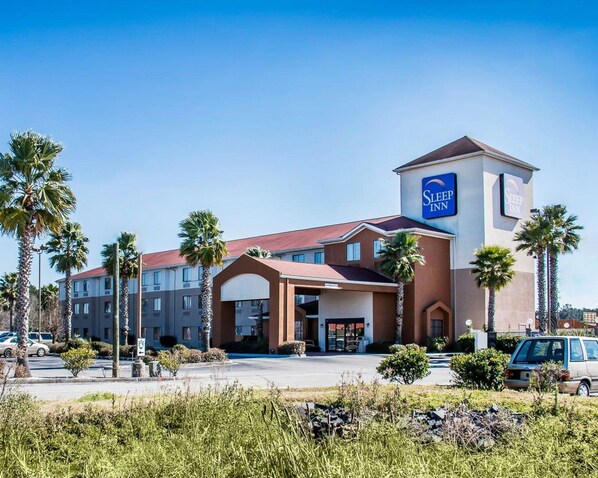A Sleep Inn hotel with a central tower, multiple buildings, and palm trees.