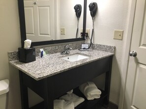 A bathroom with a granite countertop sink, a mirror, a towel rack, and a hairdryer mounted on the wall. - Sleep Inn Hardeeville - I-95 (Hardeeville)