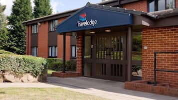 Un hôtel Travelodge avec une façade en briques, de grandes fenêtres et une entrée abritée.
