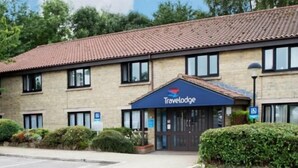 A Travelodge hotel with a tiled roof, a blue awning, and a parking lot. - Travelodge Beckington (Frome)