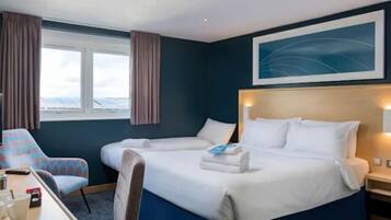 A hotel room with two beds, a desk with a chair, a window with curtains, and a painting on the wall.