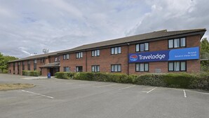 A Travelodge hotel with a brick facade, multiple windows, and a sign indicating the location as Bristol Severn View M48.