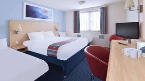 A hotel room with a large bed, a desk with a TV, and a red chair. - Travelodge London Balham (London)