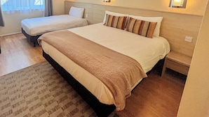 A hotel room with two beds, a large window with curtains, and wall-mounted lights. - Travel Plaza Hotel (Kettering)