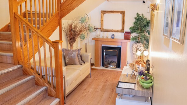 A wooden staircase leading to a living room with a fireplace, a sofa, and a coffee table with decorative items. - Travel Plaza Hotel (Kettering)