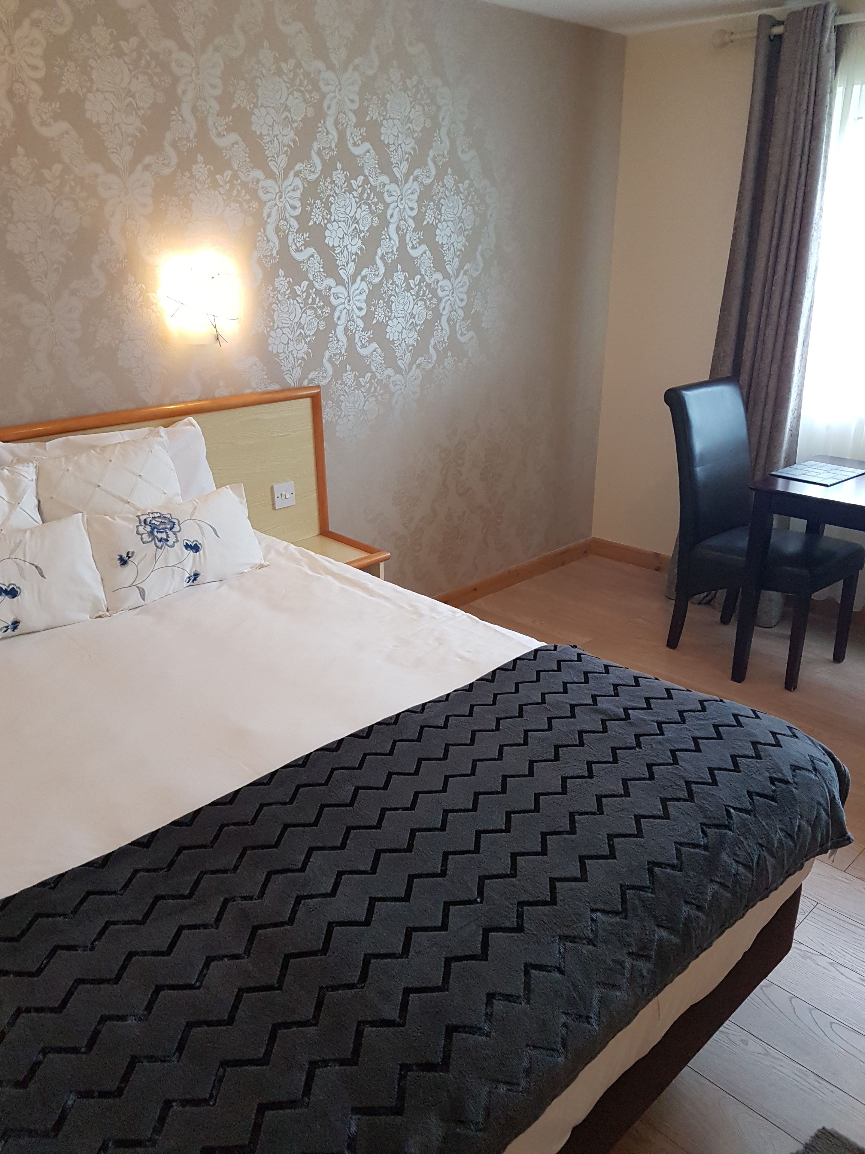 A hotel room with a bed, a desk, and a chair.