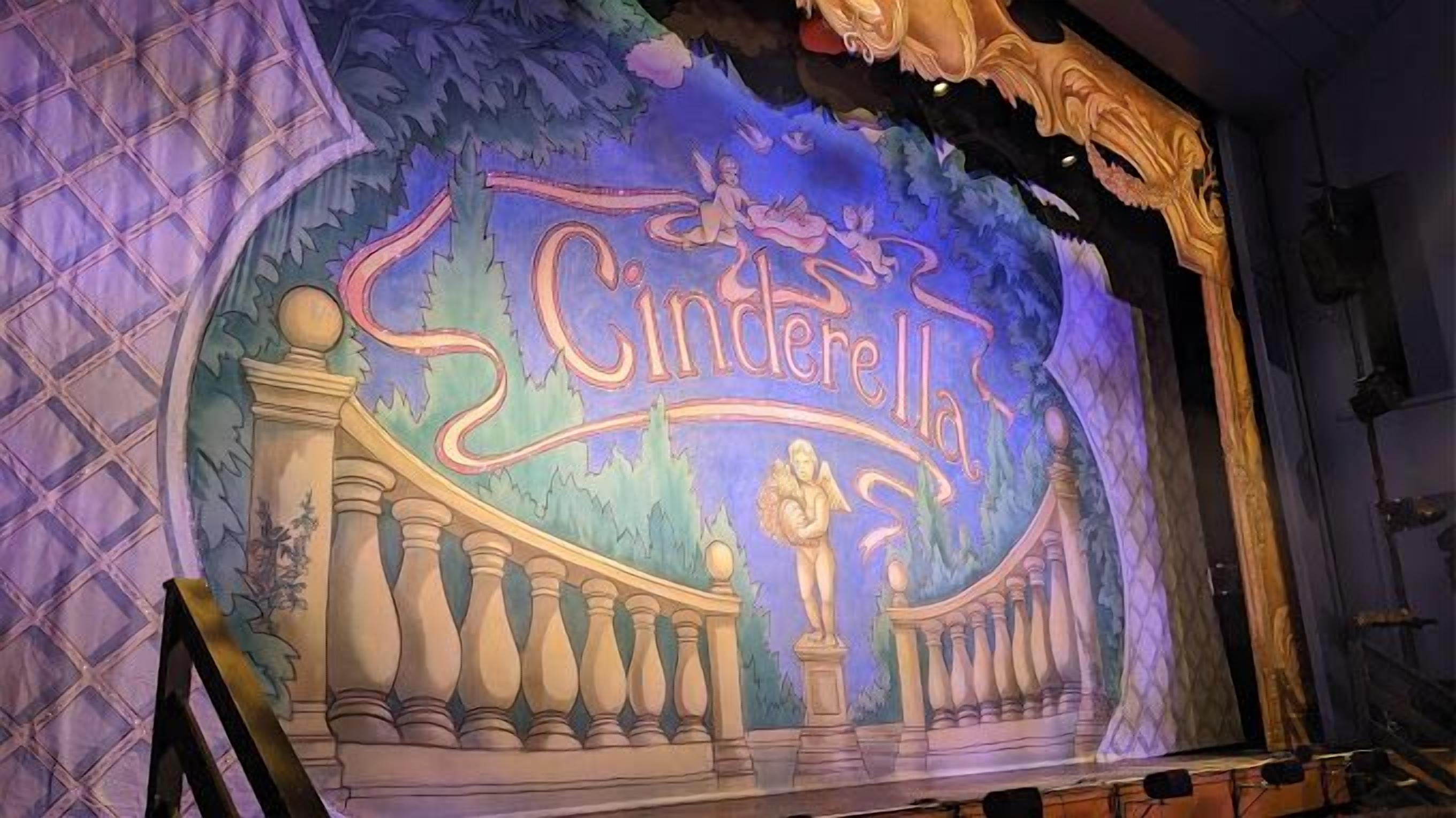 En scene med baggrundstapet der viser ordet "Cinderella" og et eventyrlandskab.