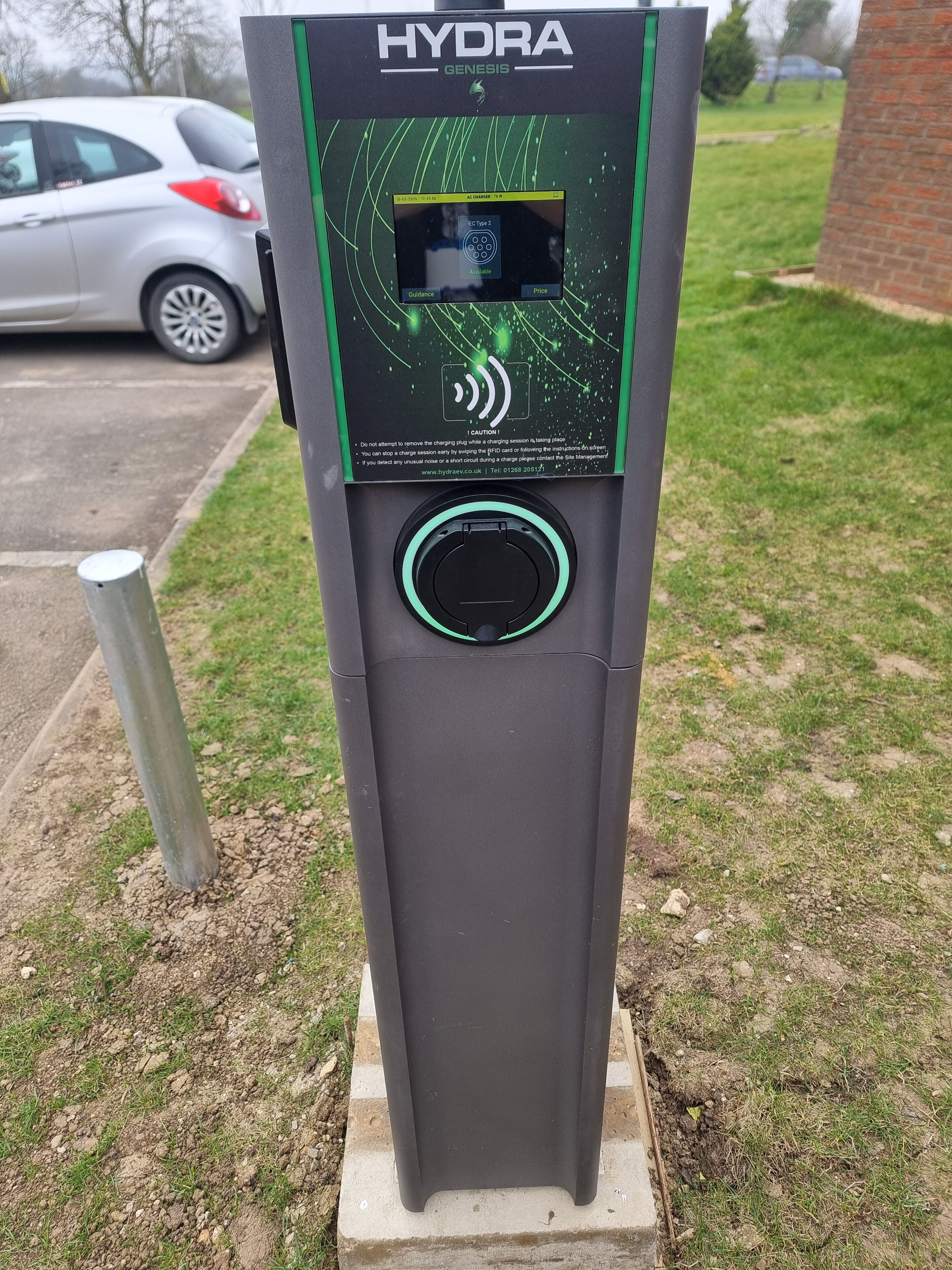 Estación de carga para vehículos eléctricos HYDRA GENESIS con pantalla digital, puerto de carga y señal de advertencia.