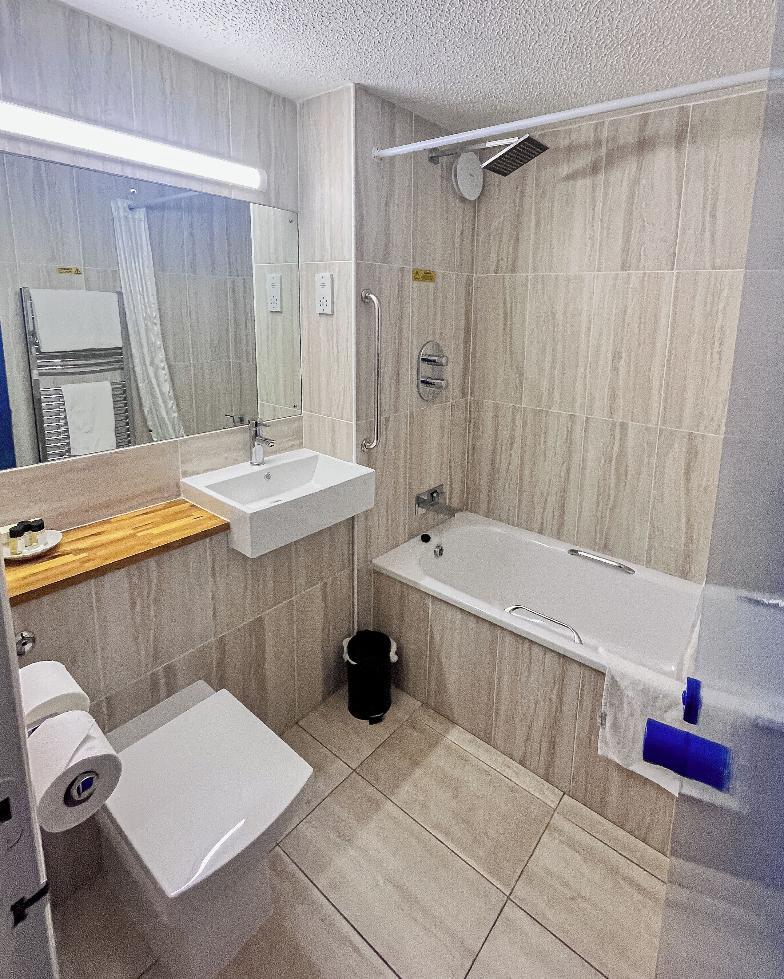 A modern bathroom with a sink, mirror, and bathtub.