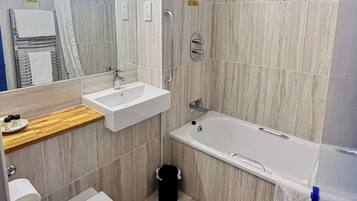 A modern bathroom with a sink, mirror, and bathtub.