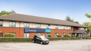 A Travelodge hotel with a brick facade, a parking lot, and a clear blue sky. - Travelodge Nottingham Trowell M1 (Nottingham)