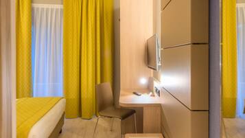 Ein modernes Hotelzimmer mit Bett, Schreibtisch, Stuhl und Fernseher.