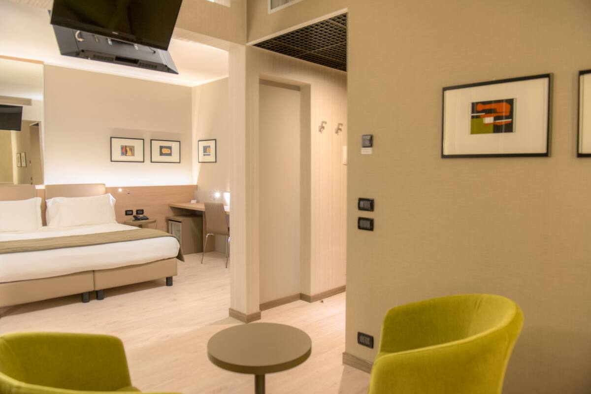 Ein Hotelzimmer mit einem Bett, einem Schreibtisch, einem Sessel und einem kleinen Tisch.