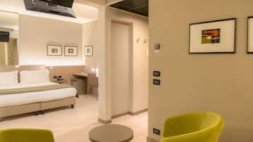 A hotel room with a bed, a desk, a chair, and a small table.
