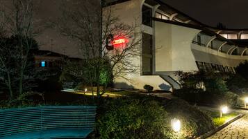 Un edificio moderno con un llamativo letrero rojo, un banco y senderos bien iluminados.