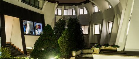 A multi-level atrium with a staircase, large windows, and potted plants.