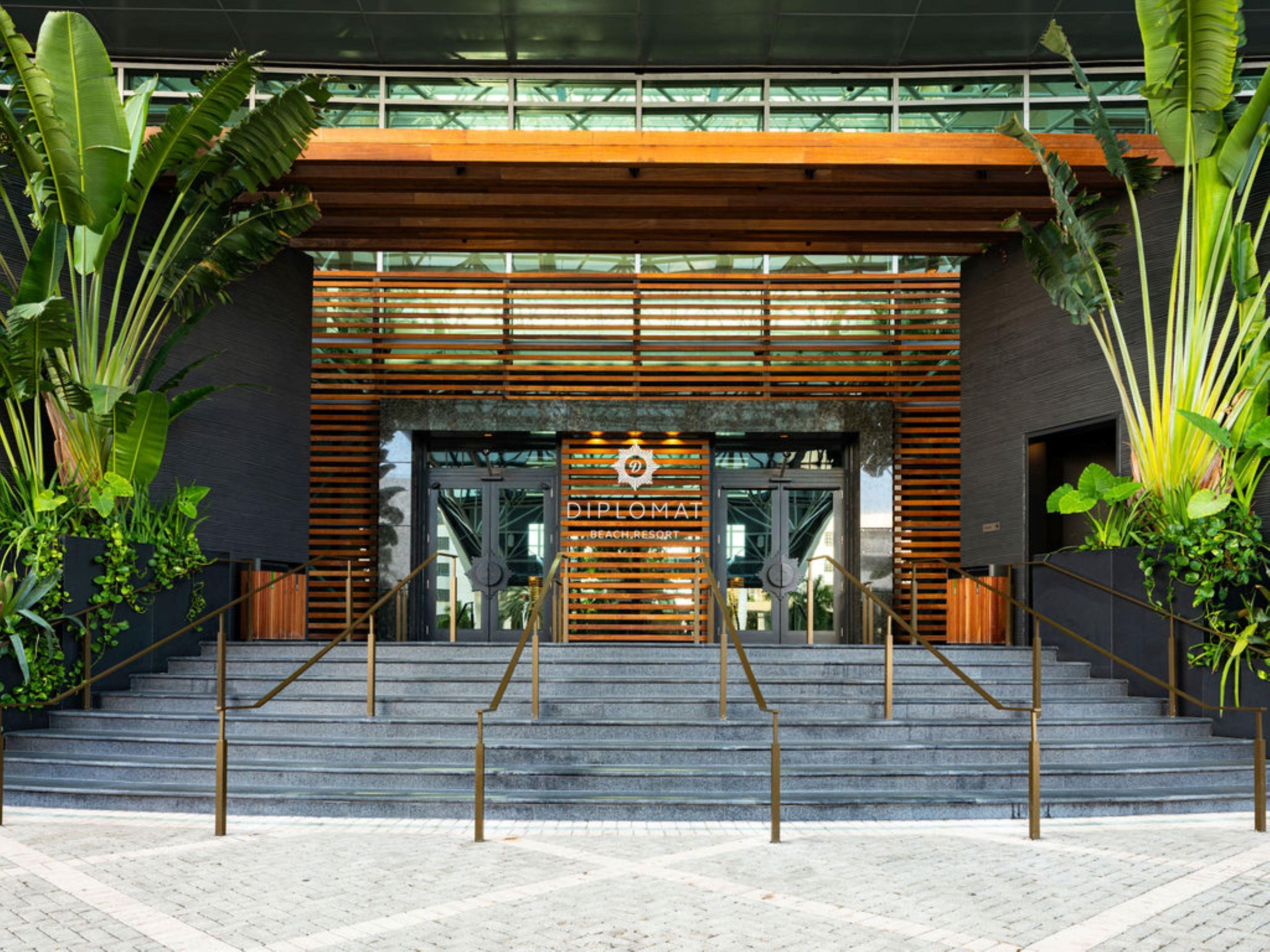 A modern building entrance with a sign reading 'DIPLOMAT BEACH RESORT'.